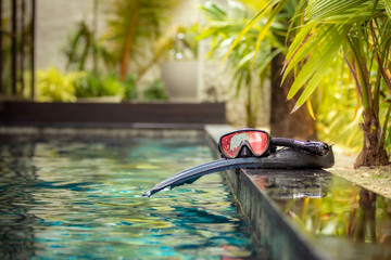 Swimming flippers and snorkeling mask laying on the edge of the pool