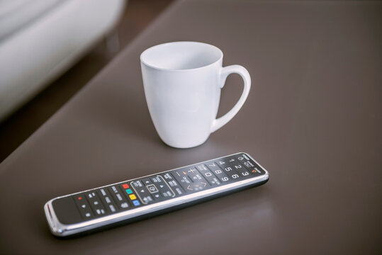 Remote control with coffee cup on table, Munich, Bavaria, Germany