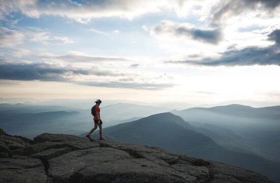 Trail runner man walking along ridge with mountains