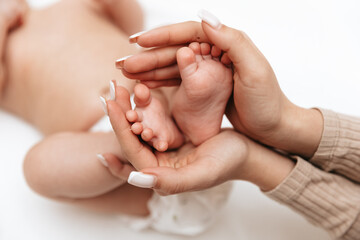 Little baby feet in mother's hands in the shape of a heart. Mom and baby.	