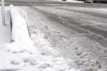 踏み荒らされて汚れた車道の雪と歩道に積もった雪 (Dirty snow on the roadway and sidewalk after being trampled)