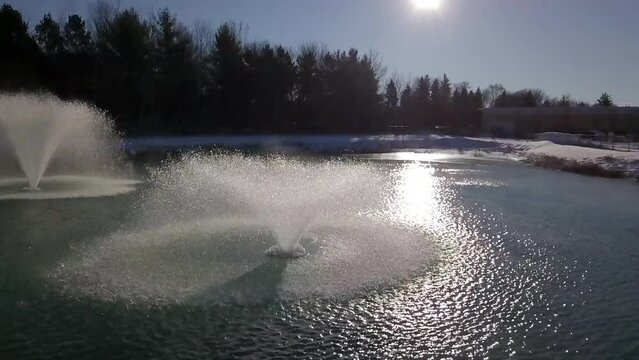 Aerial Shot Of Water Fountain In Rippled Pond, Drone Flying Forward During Winter Season - Minneapolis, Minnesota