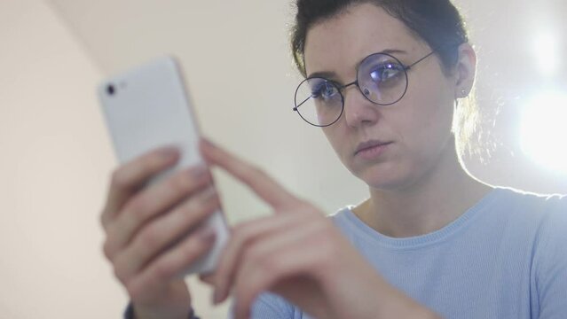Concentrated woman in eyeglasses reading comments to posts in social networks