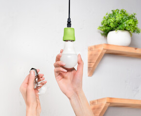 female hands screw in an energy-saving LED light bulb