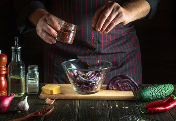 The cook adds aromatic seasoning to vegetarian food. Cooking delicious salad by the hands of the chef in kitchen. Menu idea for a hotel or restaurant