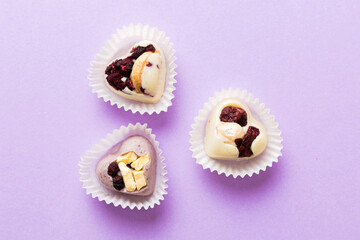 chocolate sweets in the form of a heart with fruits and nuts on a colored background. top view with space for text, holiday concept