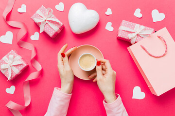 Flat lay of heart shaped cup of black coffee in the hands of women on colored background with copy space top view. Valentine day and holiday concept