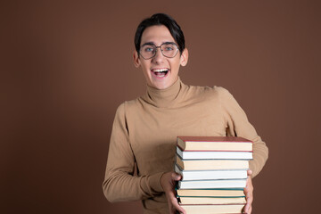 Funny young student with educational material in his hands. Emotions. Brown background.