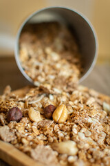 Scattering of granola with oatmeal, nuts, fruits on a wooden plate. The concept of healthy food, diet, weight loss. Closeup, selective focus, shallow depth of field