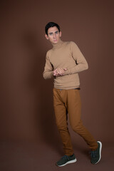 Young attractive guy fooling around in the studio. Brown background.