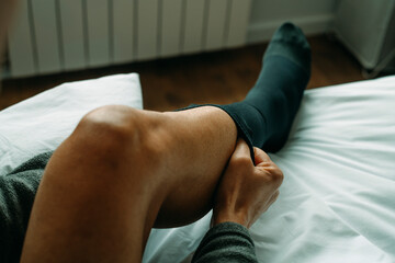 is putting on a black compression sock at home - 570202276