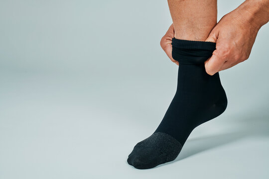 man puts on a black compression sock