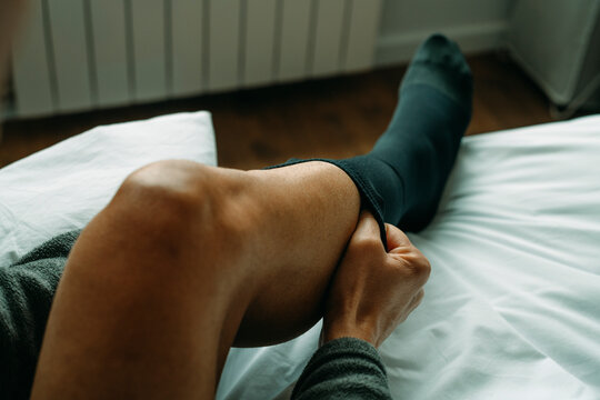 is putting on a black compression sock at home