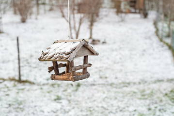 Wooden bird feeder on a tree in the winter