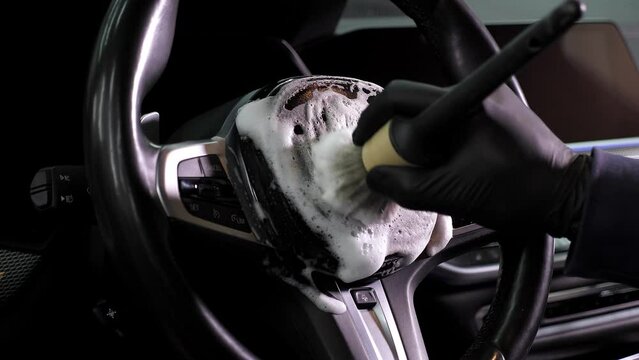 Car cleaning specialist clean with a brush and foam. Professional detailing of the car. Dry cleaning of the car interior.