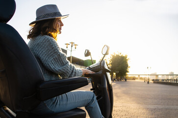 Woman tourist riding a four wheel mobility electric scooter on a city street.	