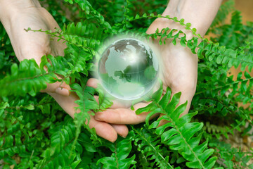 Woman  holds a model of planet Earth from glass. Symbol of sustainable development and renewable...