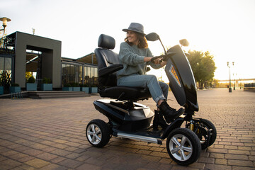 Woman tourist riding a four wheel mobility electric scooter on a city street.  © scharfsinn86