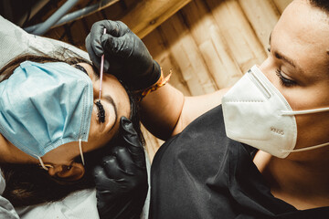 beautician working with mask and protective screen for the virus COVID