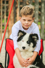 Boy in white clothes hugging a fluffy sitting husky dog © Cavan