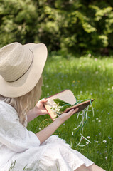 Girl in a hat with a book and lilies of the valley.