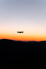Drone flying with mountains in the background during sunrise