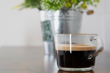 Delicious cup of black coffee with foam on a wooden table
