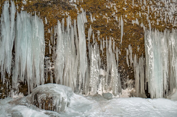 Icy stalagmites created from the side of a mountain next to the Kvernufoss waterfall, surrounded...