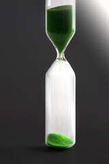 Hourglass with green sand on a dark background.