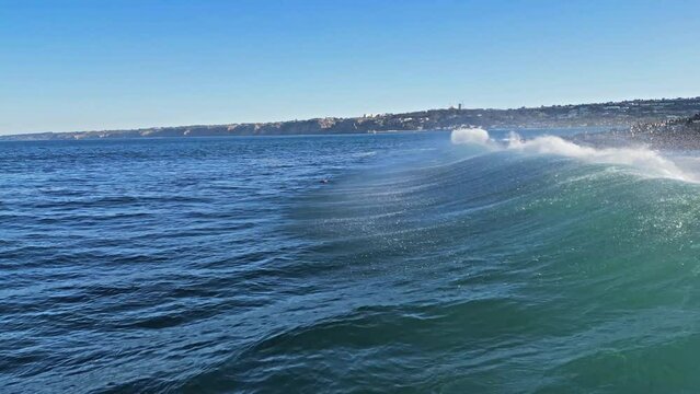 Drone shot showing horizonline of wave breaking on rocks while Sea Lions jumps out of the water during King Tide in La Jolla, California.