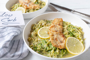 Low carb fish dish with creamy zucchini noodles or zoodles on a plate