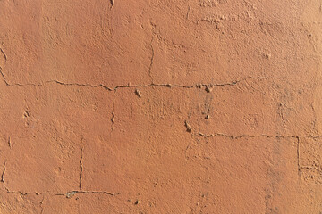 Wall painted orange with cracks in the plaster caused by the action of time. Beautiful texture.