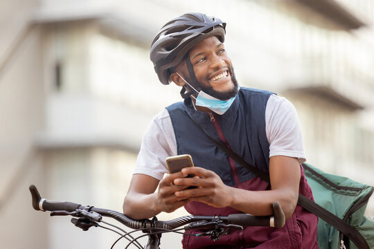 Courier service, delivery and black man with smartphone, shipping app with happy employee outdoor. Eco friendly travel, outdoor and communication with ecommerce and bike, retail and distribution