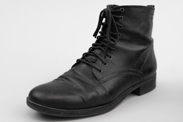 Slightly worn black shoe boot in leather with shoelaces. isolated by a gray background.