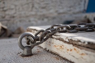 Close up of a chain in an old wooden environment, paint is peeling