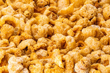 High angle closeup view of homemade crispy deep fried pork rinds in horizontal format background.