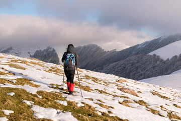 Hiker walking towards the misty top through snowy fields