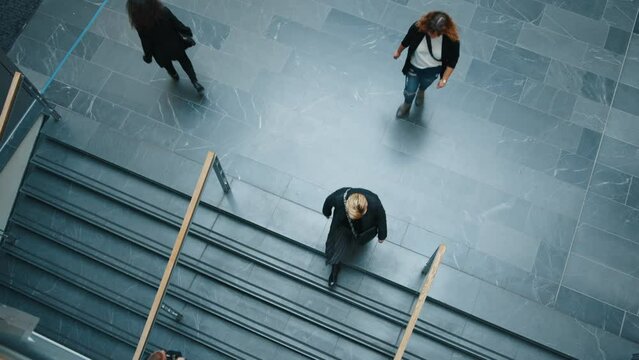 Busy day at the office: View from above of working professionals walking on a corporate building