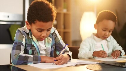 Cute primary school boys kids studying using laptop computer together at home kitchen Adorable african american brothers doing homework writing exercise in notebook indoors Distance online education - Powered by Adobe