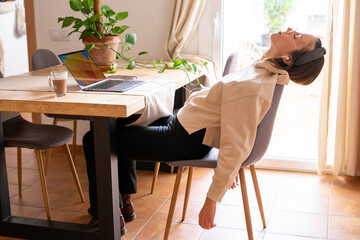 girl working at home. Girl leaning on the chair and letting her arms drop from exhaustion