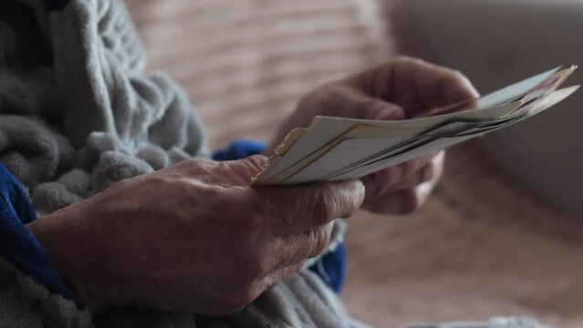 close-up in the hands of a pensioner holding old photos, an elderly man reminisces about the past by looking at family old photos. nostalgia concept, family tree.selective focus