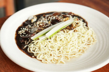 Jjajangmyeon is Korean noodles with black bean sauce. Served on white plate.