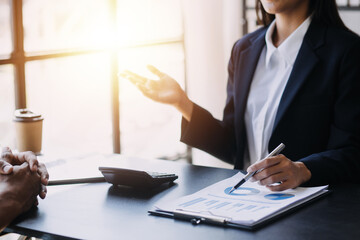 Asian Business woman using calculator and laptop for doing math finance on an office desk, tax, report, accounting, statistics, and analytical research concept