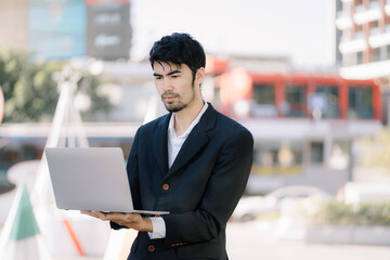 Portrait of Asian businessman holding laptop.Office worker at business center.