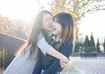 Happy lifestyle of a young Asian couple playing with each other outside. A girl pulls herself to...