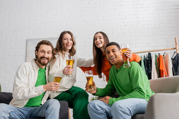 cheerful women hugging with interracial men holding glasses of beer