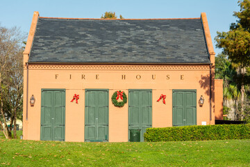 Red brick and green wooden doors of an old and abandoned fire house decorated for Christmas in...