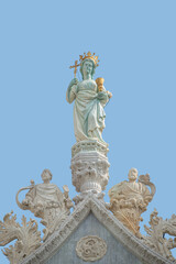Fototapeta na wymiar Cover page with ancient statue of Maria with cross and holy grail at the roof top decoration of Doge Palace in Venice, Italy, at blue sky background with copy space. Concept of architecture heritage