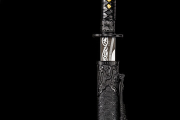 Long Chinese sword with black scabbard isolated on black background.