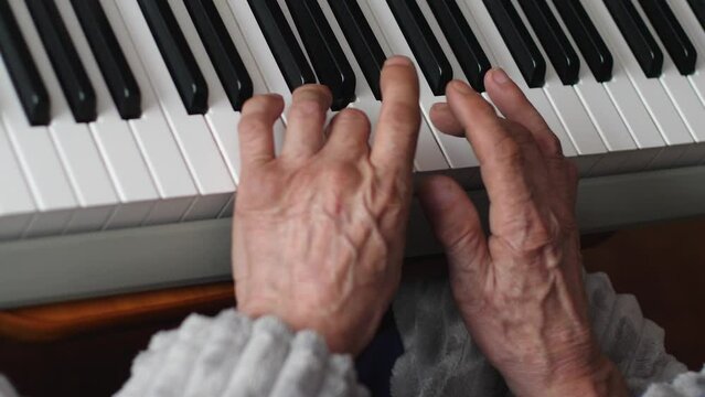 hands of a pensioner playing the piano while at home. an elderly man practices playing a musical instrument, an elderly man's hobby is playing the synthesizer